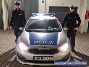 dwuosobowy patrol policji stoi przy radiowozie