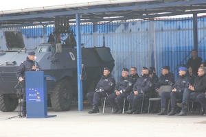 Zastępca Komendanta Głównego policji przemawia stojąc przy mównicy do policjantów siedzących na krzesłach pod namiotem
