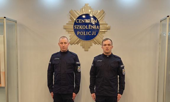 dwaj umundurowani słuchacze szkoły Policji pozują do zdjęcia, w tle na ścianie widać logo Centrum Szkolenia Policji