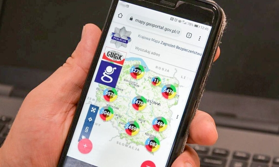 na ekranie smartfona trzymanego w dłoni wyświetlana jest strona Krajowej Mapy Zagrożeń Bezpieczeństwa