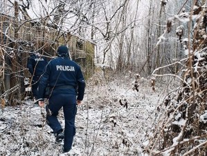 policjanci przechodzą przez zarośla do drewnianego domu - widok z tyłu. Naokoło leży śnieg