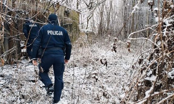 policjanci przechodzą przez zarośla do drewnianego domu - widok z tyłu. Naokoło leży śnieg