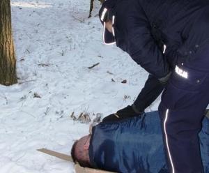 umundurowany policjant nachyla się nad leżącym na ziemi mężczyzną