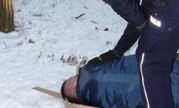 umundurowany policjant nachyla się nad leżącym na ziemi mężczyzną