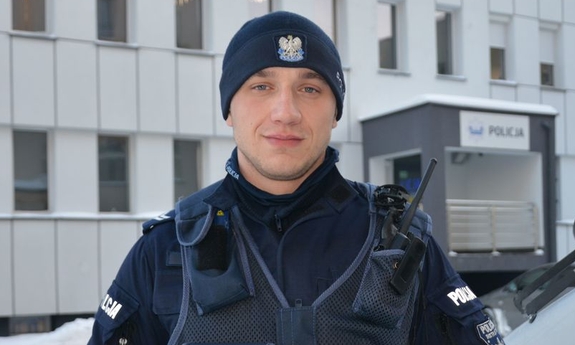 policjant stoi przed budynkiem komendy policji