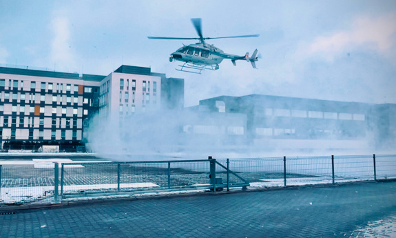 Policyjny śmigłowiec lądujący na przyszpitalnym lądowisku.