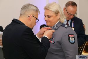 mężczyzna w garniturze przypina policjantce odznaczenie