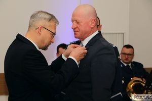 mężczyzna w garniturze przypina drugiemu mężczyźnie odznaczenie