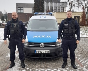 umundurowani policjanci stoją przy radiowozie