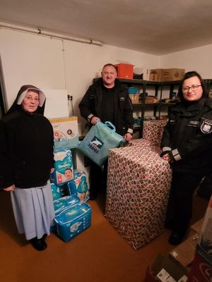 Policjanci pozują do zdjęcia z siostrą zakonną, obok stoją przywiezione przez nich prezenty.