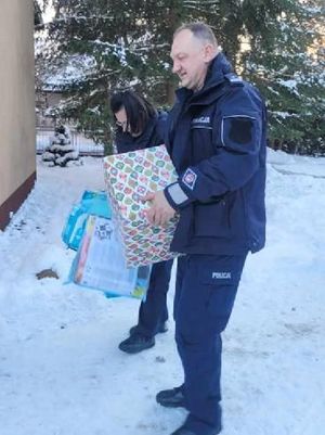 Policjanci wnoszą przywiezione prezenty.