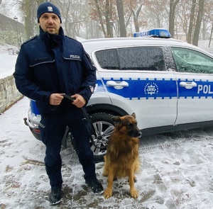 policjant z psem stoi przy radiowozie policyjnym