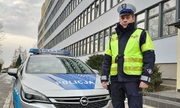 policjant stoi przy radiowozie stojącym przed budynkiem
