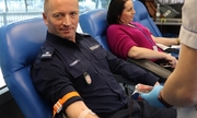 policjant i kobieta w trakcie oddawania krwi