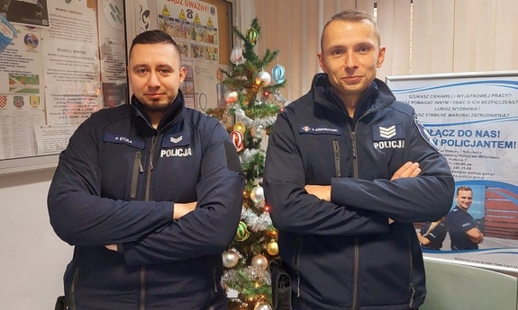 Dwaj policjanci w pomieszczeniu, w tle choinka  świąteczna