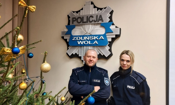 umundurowana policjantka i policjant stoją przy choince, w tle logo policji