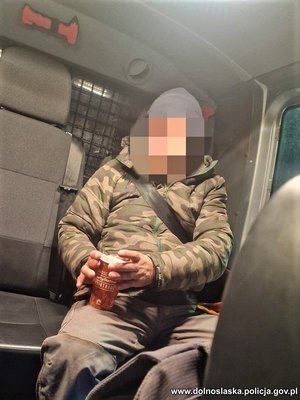 uratowany mężczyzna siedzi w radiowozie, w ręku trzyma kubek z ciepłym napojem