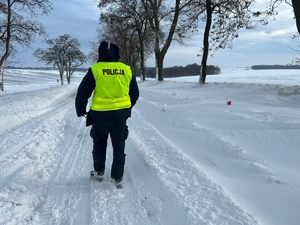 policjant na zasypanej śniegiem drodze