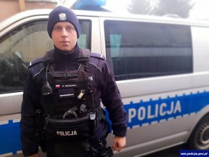 policjant stoi przy radiowozie