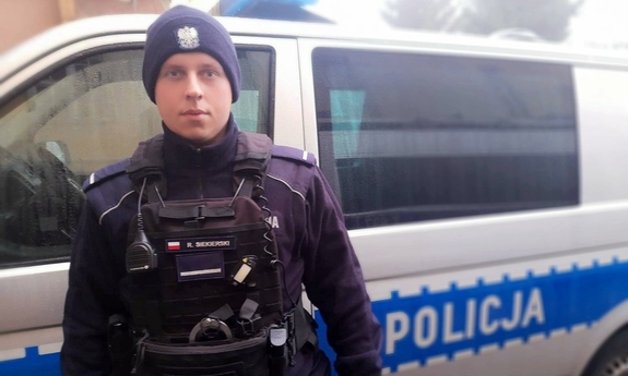 policjant stoi przy radiowozie