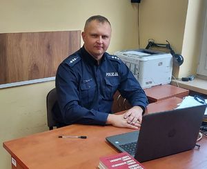 siedzący za biurkiem umundurowany policjant