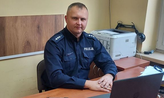 siedzący za biurkiem umundurowany policjant