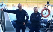 dwaj policjanci na łodzi policyjnej przycumowanej do brzegu