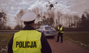 dwóch umundurowanych policjantów, dron i radiowóz