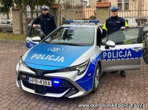 dwaj policjanci stojący przy radiowozie