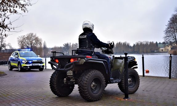 policjant na quadzie, z tyłu widoczny policyjny radiowóz