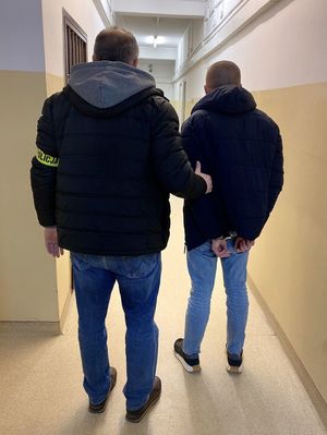 policjant prowadzi zatrzymanego - widok z tyłu