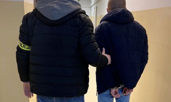 policjant prowadzi zatrzymanego - widok z tyłu