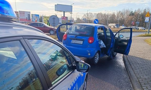 Na zdjęciu widać radiowóz, przed który stoi zatrzymany w wyniku pościgu samochód. W tle widać policjanta, który kieruje ruchem