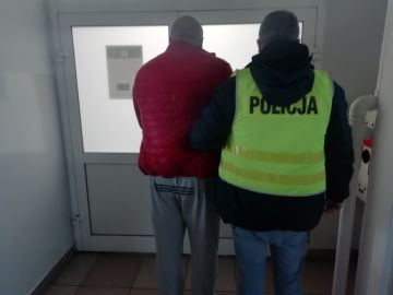 Mężczyzna i policjant w kamizelce na tle drzwi - widok z tyłu