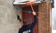 policjant usuwa śnieg z dachu werandy przy pomocy łopaty do śniegu