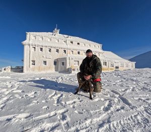 policyjny pies w goglach i jego przewodnik w ośnieżonych górach