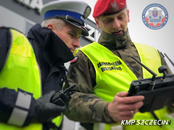 umundurowany policjant i żandarm patrzą w ekran trzymanego tableta przez jednego z nich