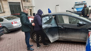 zatrzymany wsiada do nieoznakowanego radiowozu, za nim stoi policjant