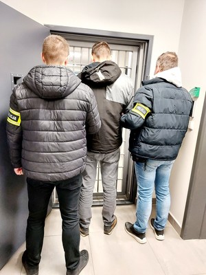 policjanci prowadzą zatrzymanego mężczyznę