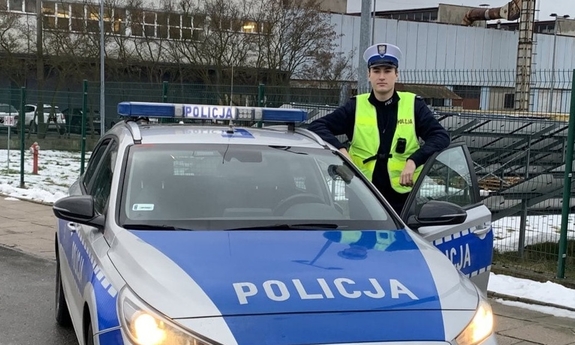 policjant stoi przy radiowozie