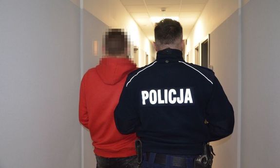 umundurowany funkcjonariusz prowadzi zatrzymanego nastolatka