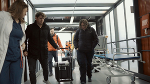 Pojemniki do transportu organów prowadzone przez mężczyzn i kobiety na szpitalnym korytarzu.