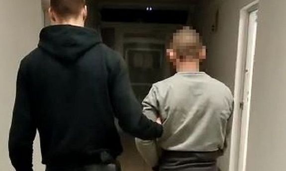 policjant ubrany po cywilnemu prowadzi zatrzymanego mężczyznę