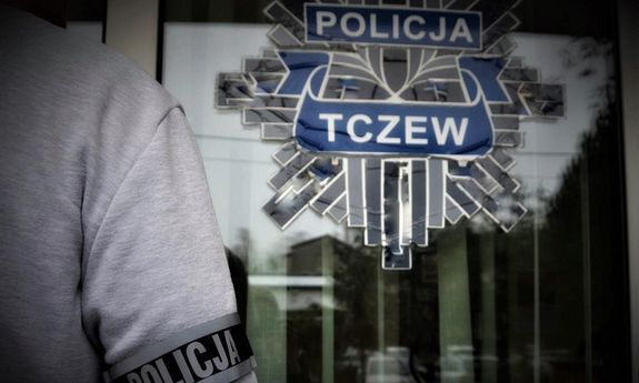 policjant stoi na tle drzwi wejściowych do jednostki policji