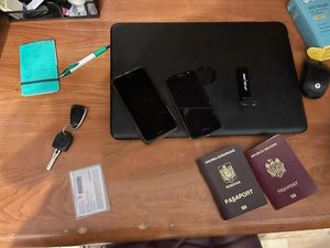 ana biurku leży laptop dwa telefony komórkowe kluczyki do samochodu notes długopis i dokument