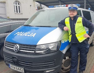 policjant stoi przy radiowozie