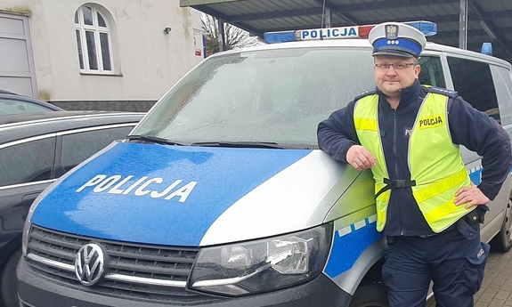 policjant stoi przy radiowozie