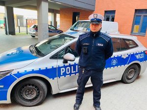 umundurowany policjant stoi przy radiowozie