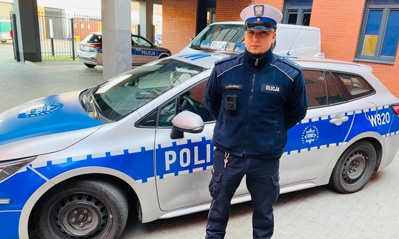 umundurowany policjant stoi przy radiowozie