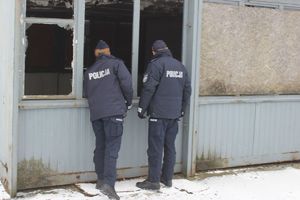 dwóch umundurowanych policjantów kontroluje pustostan